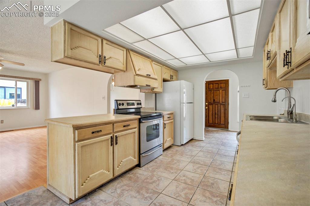 Image 7 of 45: Kitchen with arched walkways, light brown cabinetry, stainless steel electr