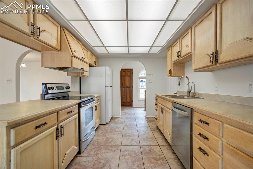 Image 8 of 45: Kitchen featuring arched walkways, stainless steel appliances, light brown 