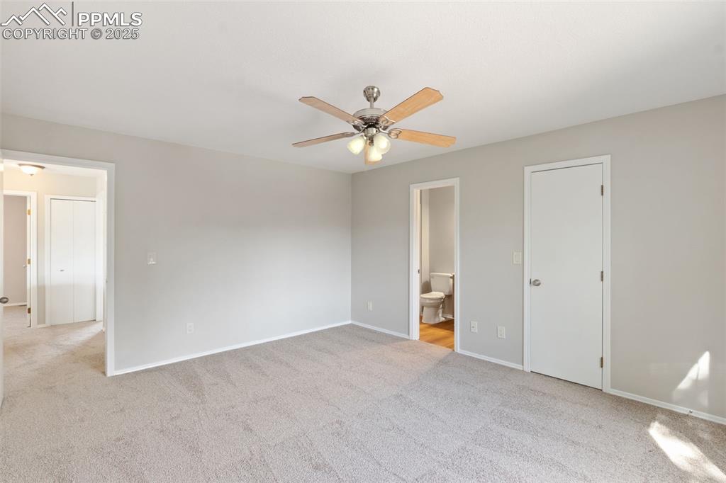 Image 15 of 31: Unfurnished bedroom with carpet, ensuite bath, and ceiling fan