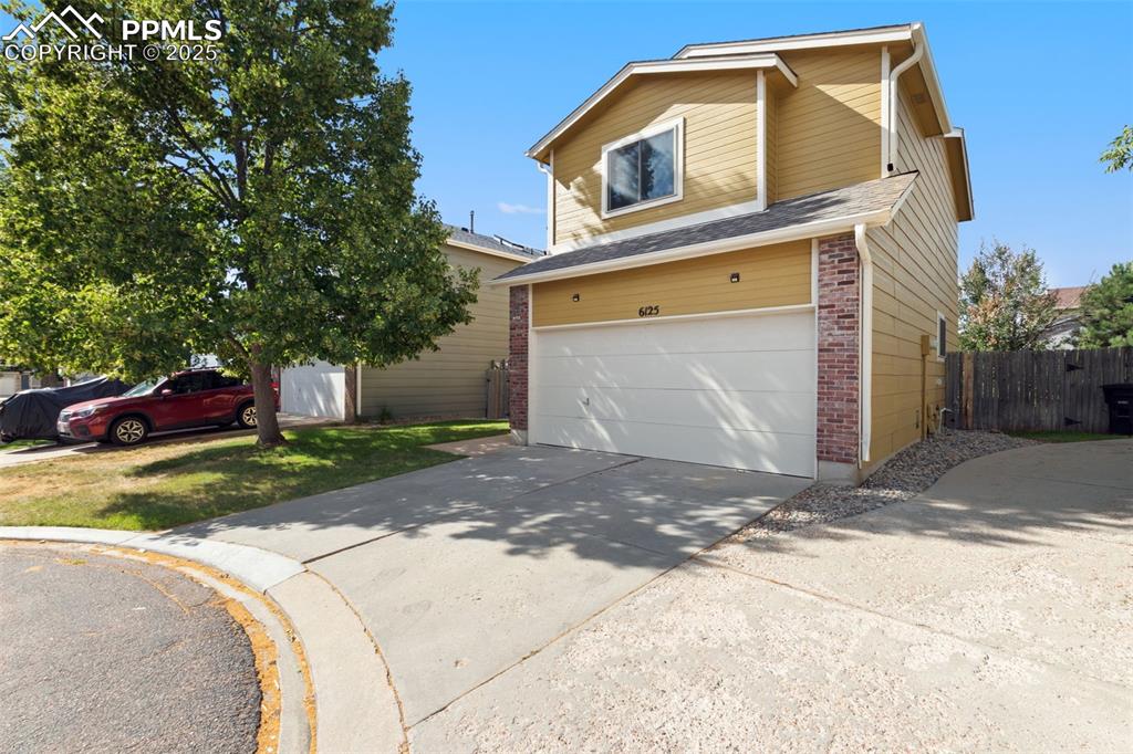 Image 2 of 31: Traditional-style house featuring brick siding, concrete driveway, and an a