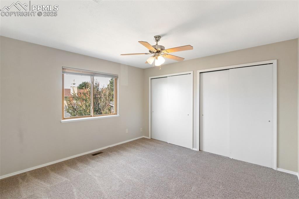 Image 20 of 31: Unfurnished bedroom with multiple closets, carpet floors, and a ceiling fan
