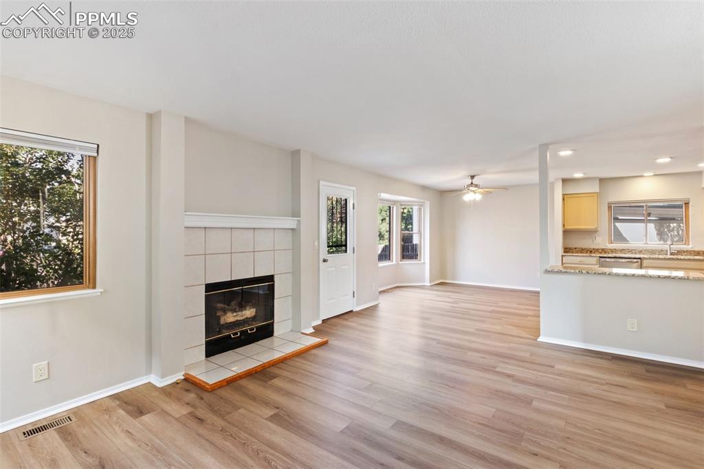 Image 3 of 31: Unfurnished living room with a tiled fireplace, light wood-style floors, re