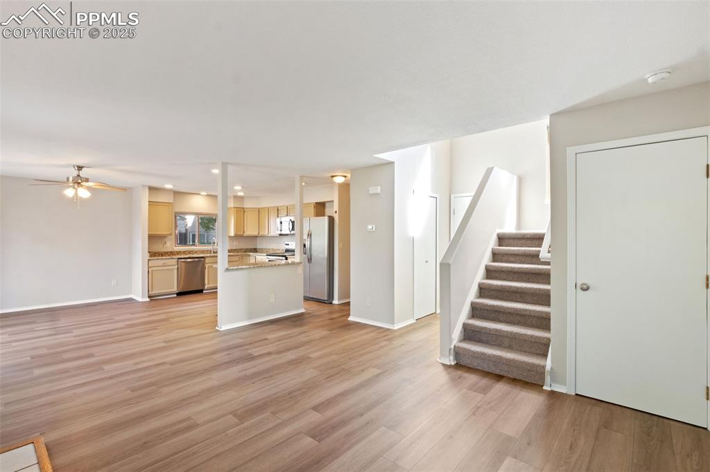 Image 4 of 31: Unfurnished living room with light wood-style floors, ceiling fan, stairs,