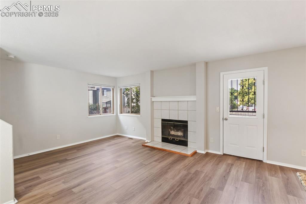 Image 6 of 31: Unfurnished living room featuring a fireplace and wood finished floors