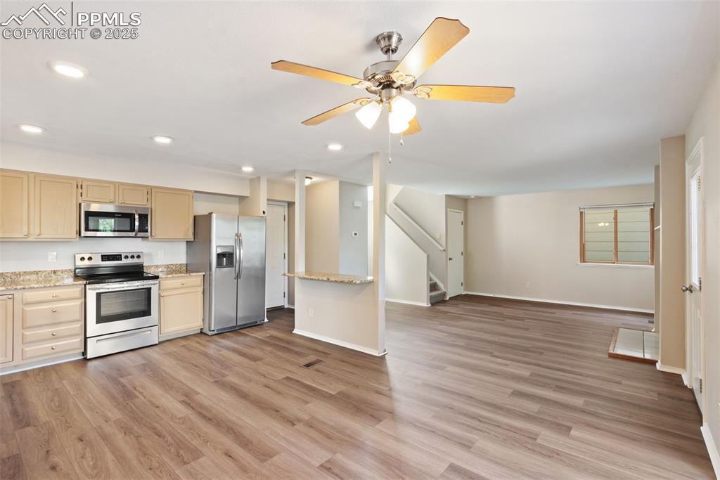 Image 7 of 31: Kitchen featuring stainless steel appliances, open floor plan, light wood f