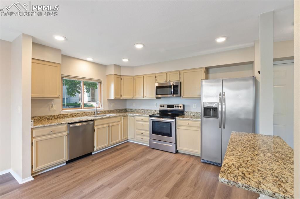 Image 9 of 31: Kitchen featuring appliances with stainless steel finishes, light wood-styl