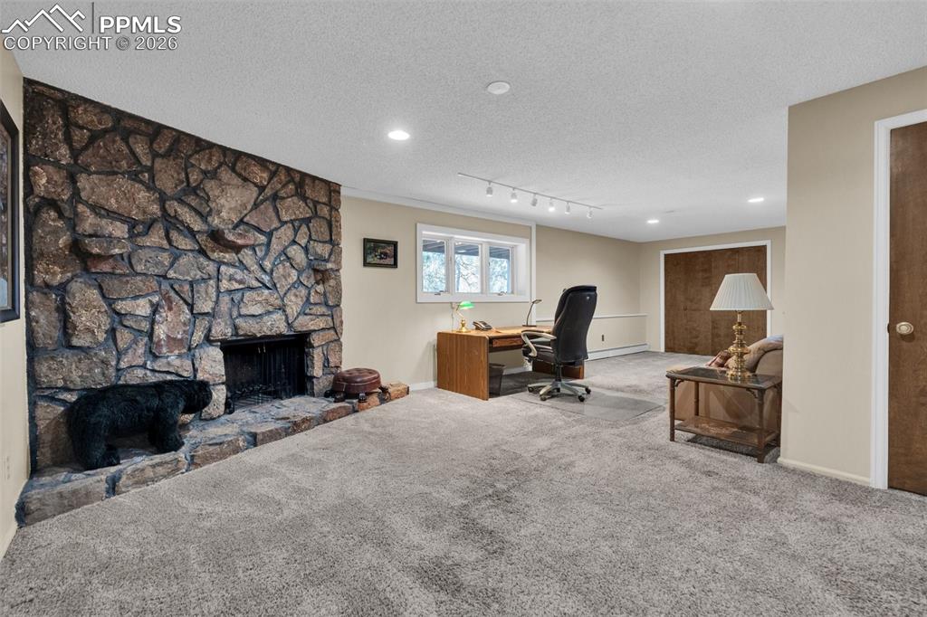 Image 45 of 49: Lower level family room being used as an office. Wood burning fireplace wit