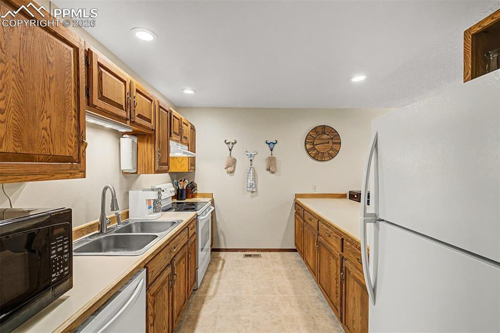 Image 13 of 23: The kitchen peninsula doubles as a gathering spot, with bar stools pulled u
