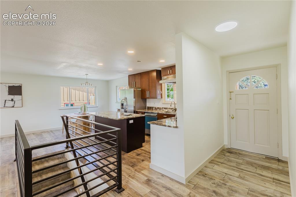 Image 13 of 47: Open-concept living area featuring wood-finish flooring, a contemporary sta