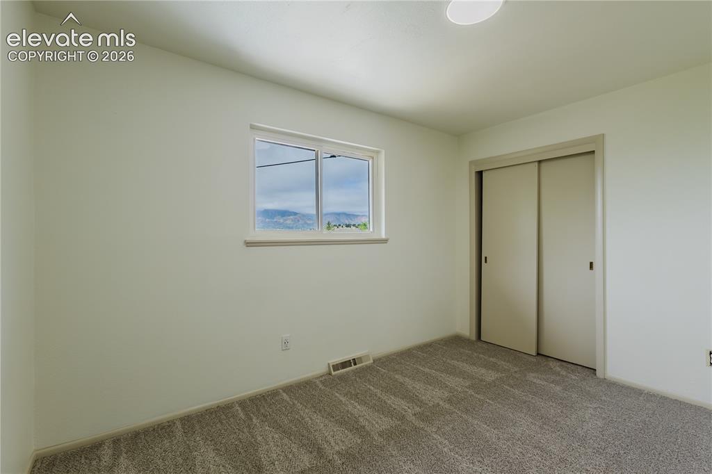 Image 21 of 47: Neutral-toned room featuring a single window, carpet flooring, and a slidin