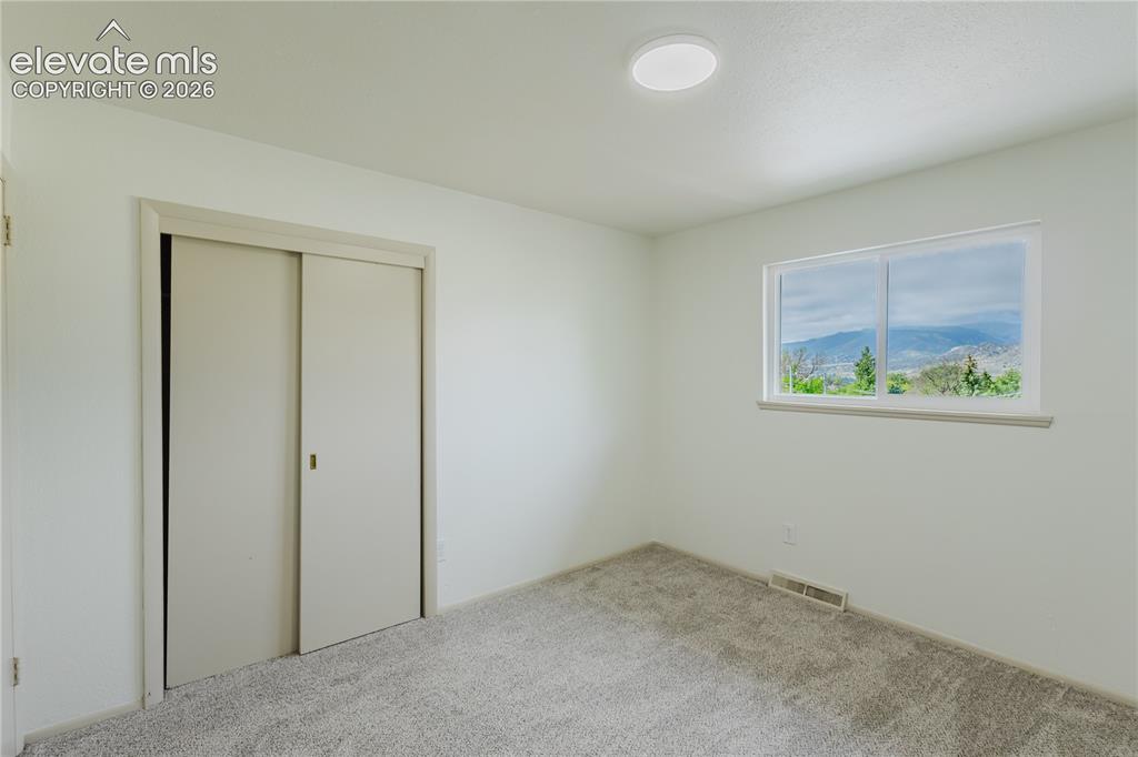 Image 23 of 47: Bright room with a large window framing distant mountain scenery