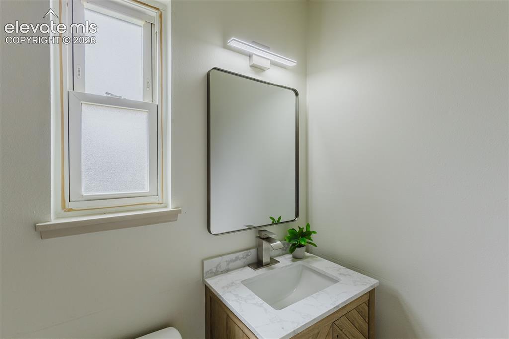 Image 25 of 47: Modern vanity with a rectangular undermount sink, a stone-finish countertop