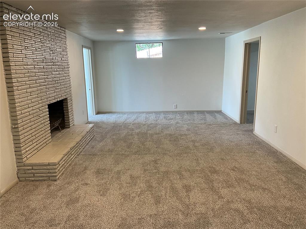 Image 44 of 47: Expansive room featuring a brick fireplace with a raised hearth, light-tone