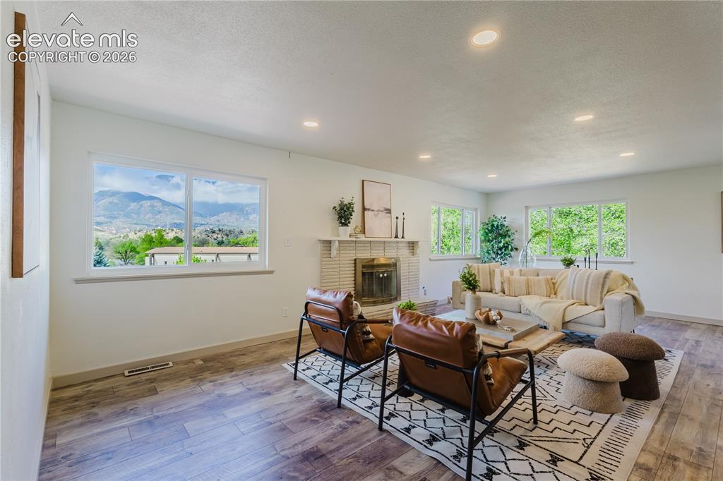 Image 5 of 47: Spacious living area featuring expansive windows, a brick fireplace, recess