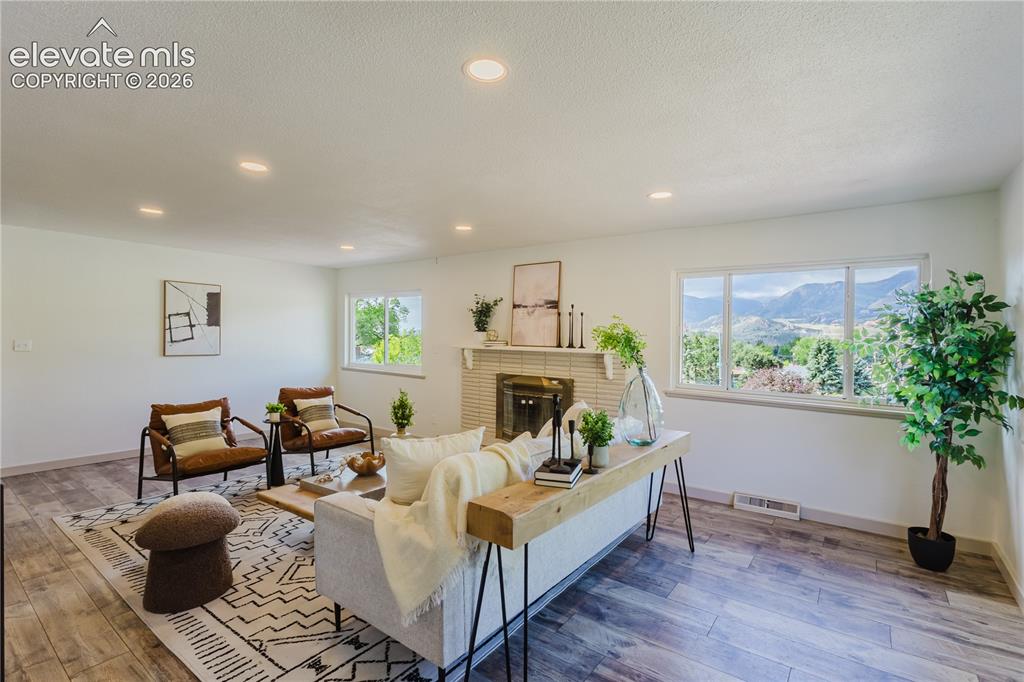 Image 8 of 47: Bright living space featuring wood-finish flooring, a contemporary fireplac