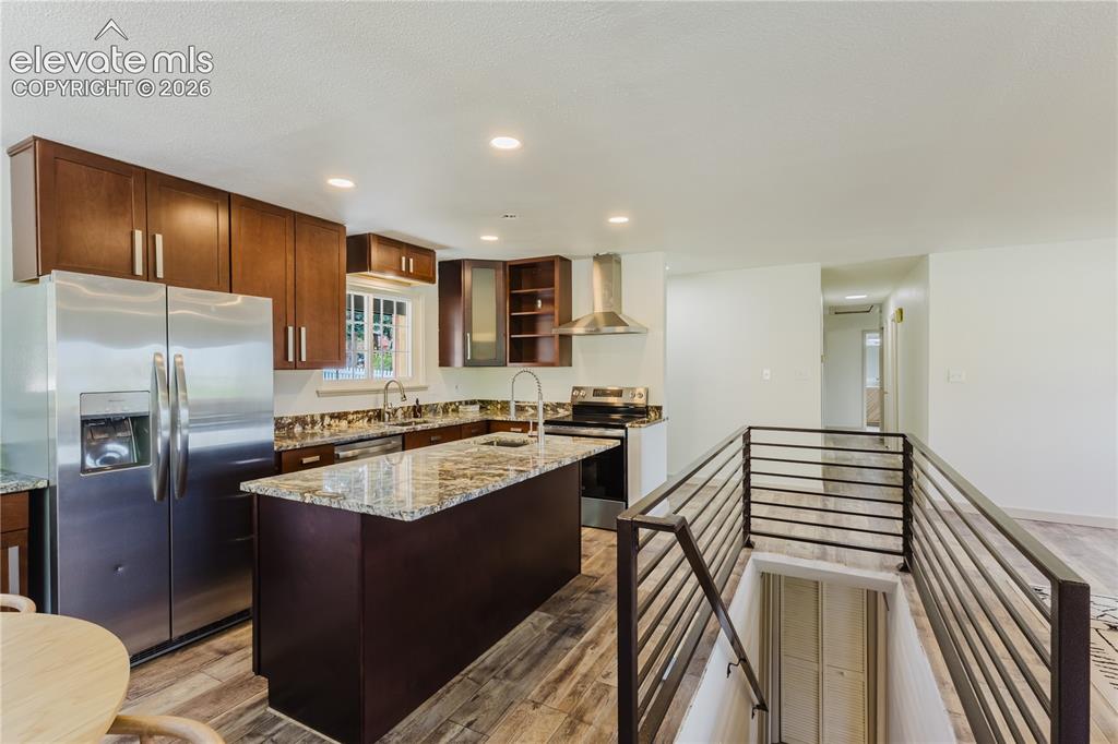 Image 9 of 47: Kitchen featuring dark wood cabinetry, stainless steel appliances, a center