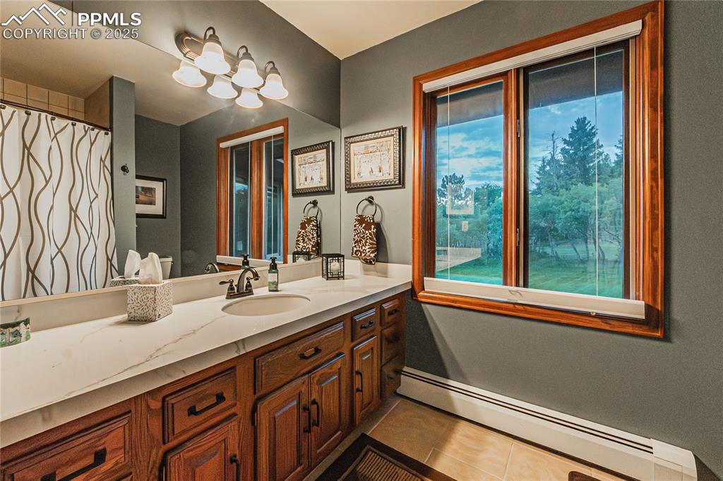 Image 15 of 39: Bathroom featuring a baseboard heating unit, vanity, tile patterned floorin