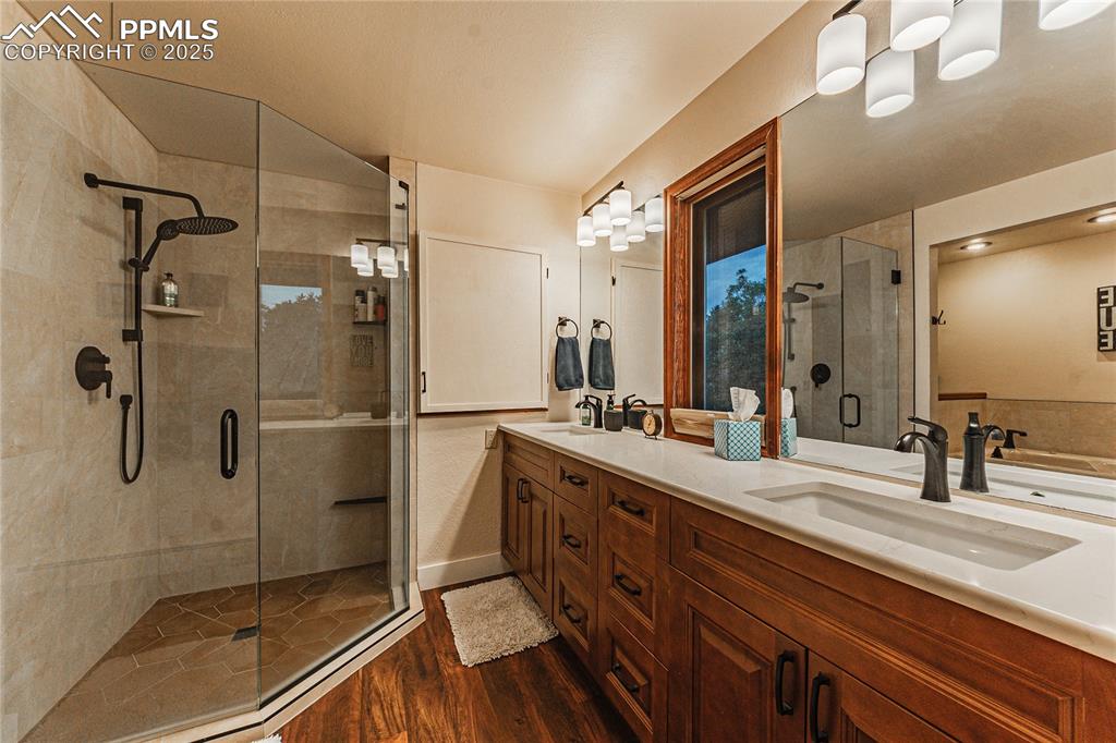 Image 20 of 39: Full bath featuring wood finished floors, a shower stall, and double vanity