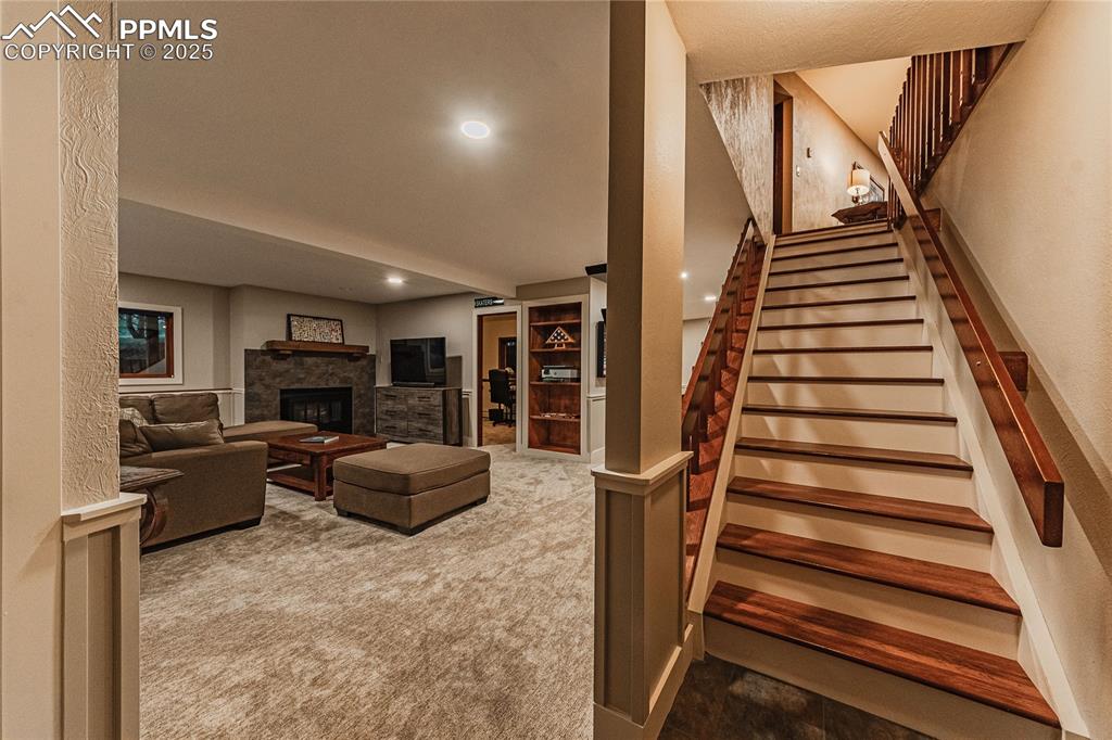 Image 22 of 39: Living room with carpet, stairs, recessed lighting, and a fireplace