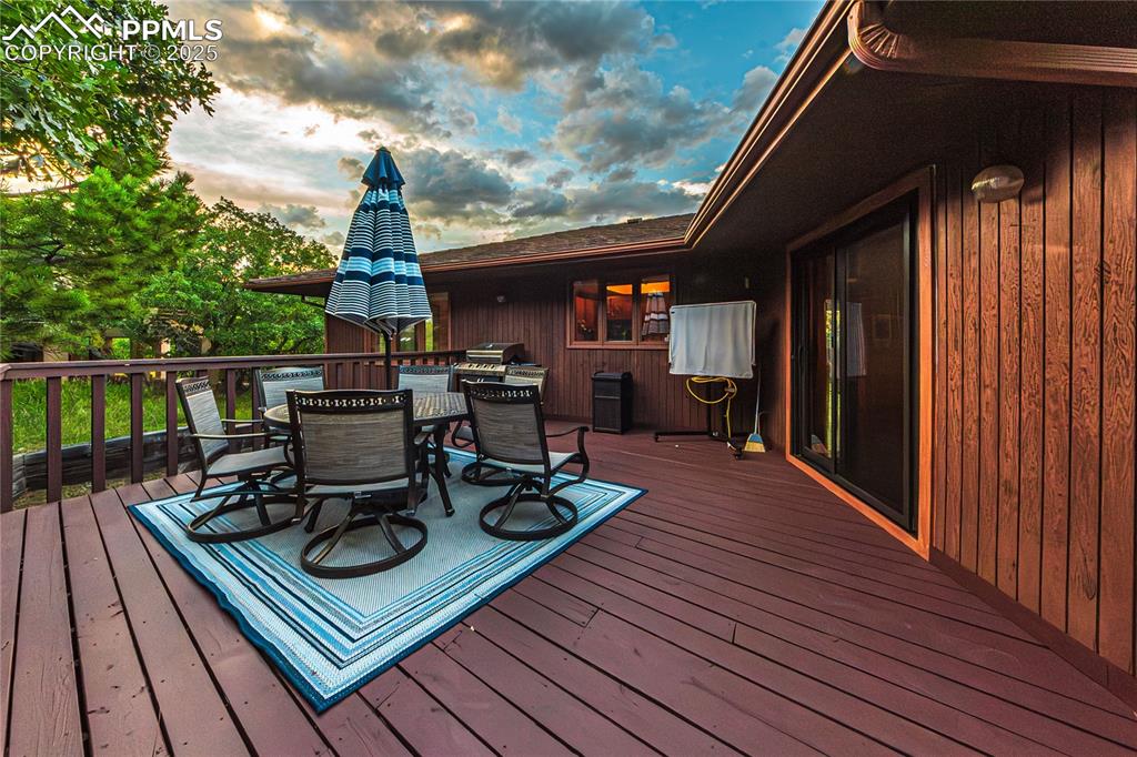 Image 32 of 39: Wooden terrace with outdoor dining space and a grill