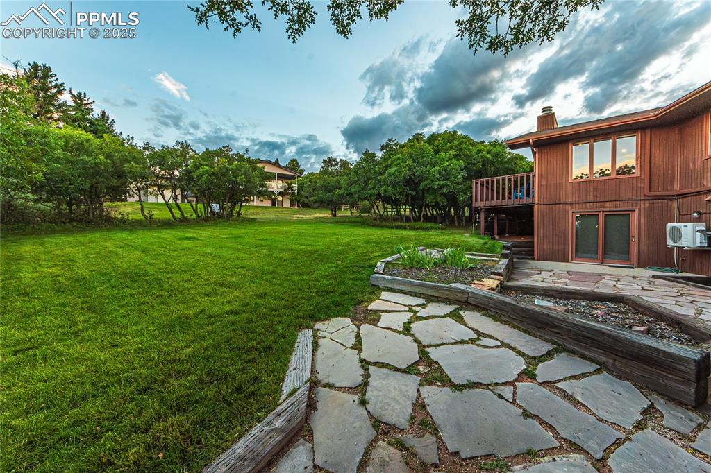 Image 38 of 39: View of green lawn with a cooling unit and a deck