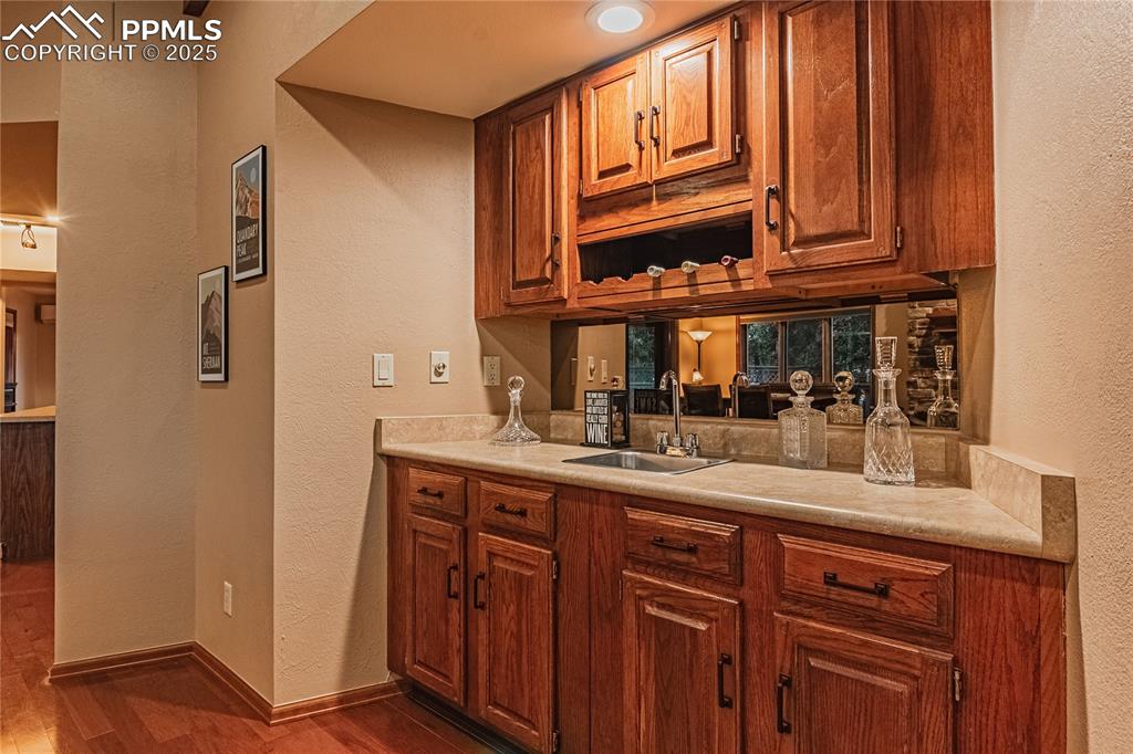 Image 6 of 39: Bar with a sink, wood finished floors, a textured wall, and baseboards