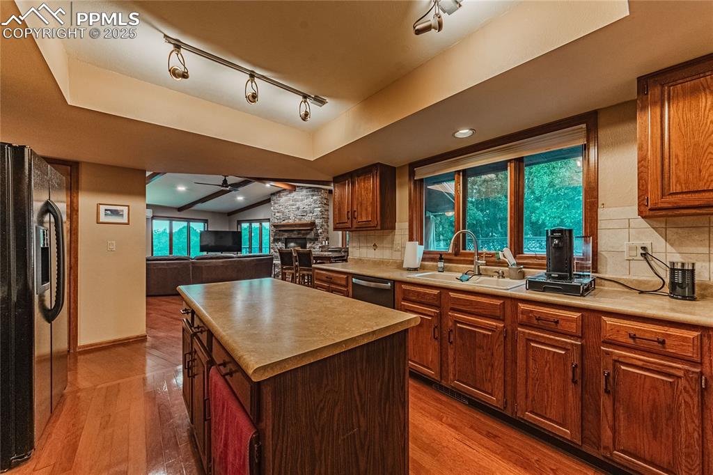 Image 8 of 39: Kitchen featuring a sink, black refrigerator with ice dispenser, a fireplac
