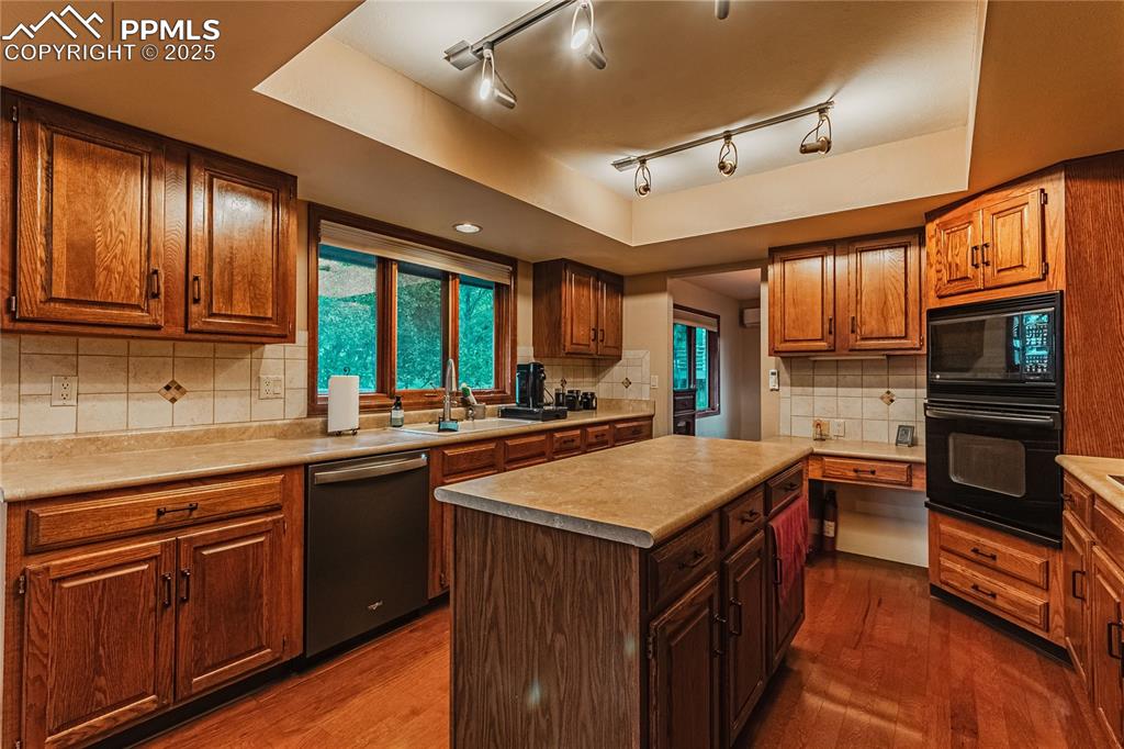 Image 9 of 39: Kitchen with black appliances, a sink, dark wood-type flooring, decorative