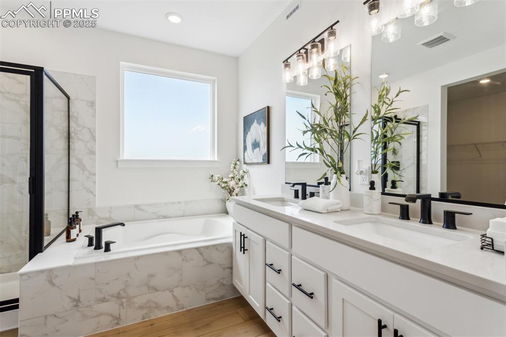 Image 13 of 23: Full bath with a shower stall, visible vents, a sink, and wood finished flo