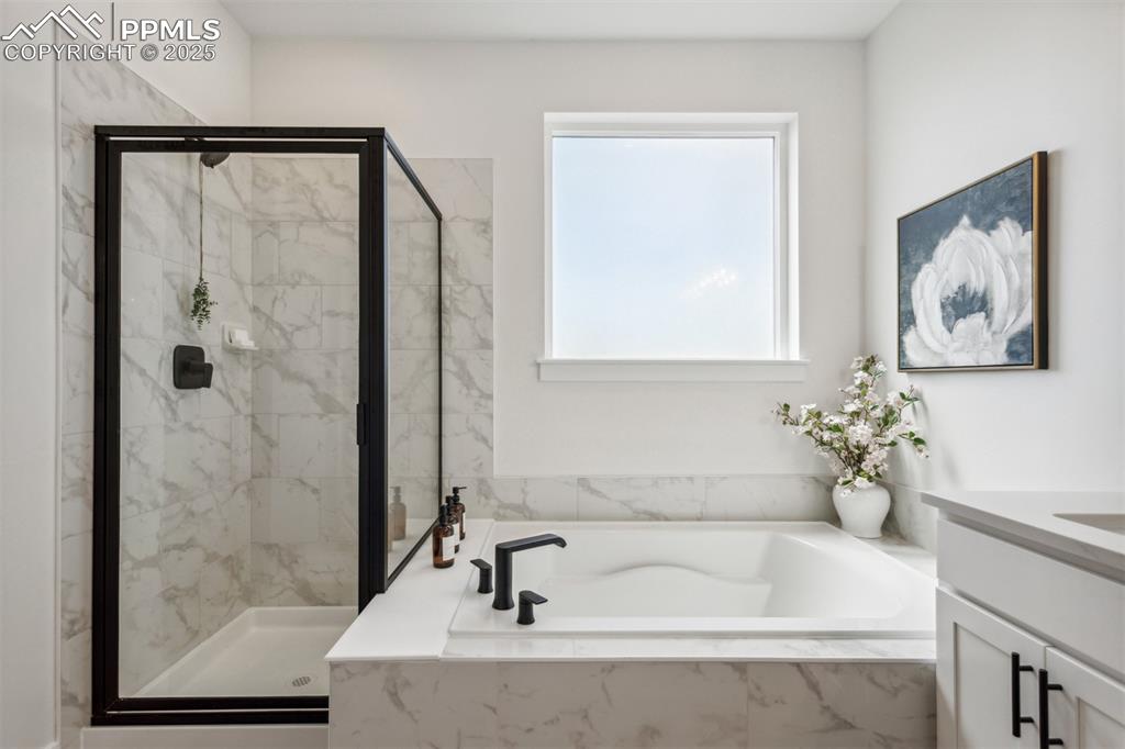 Image 14 of 23: Full bath featuring a marble finish shower, a bath, and vanity
