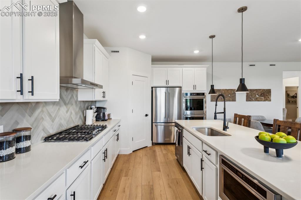 Image 3 of 23: Kitchen with light countertops, wall chimney exhaust hood, appliances with 