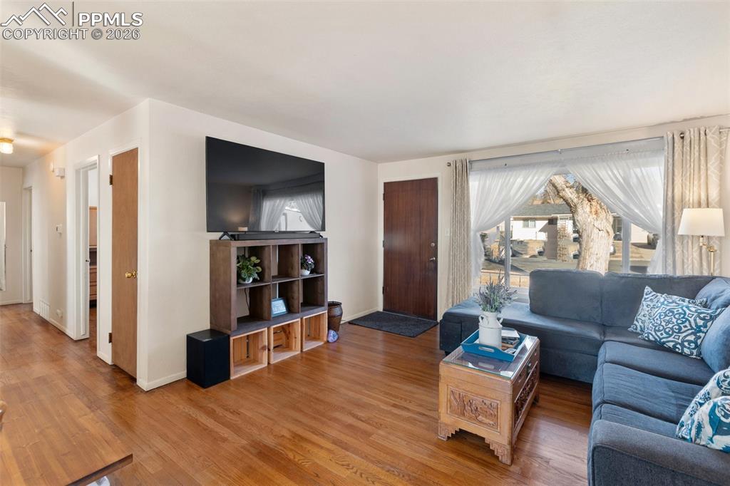Image 8 of 24: Warm and inviting living room featuring original hardwood floors, full of c