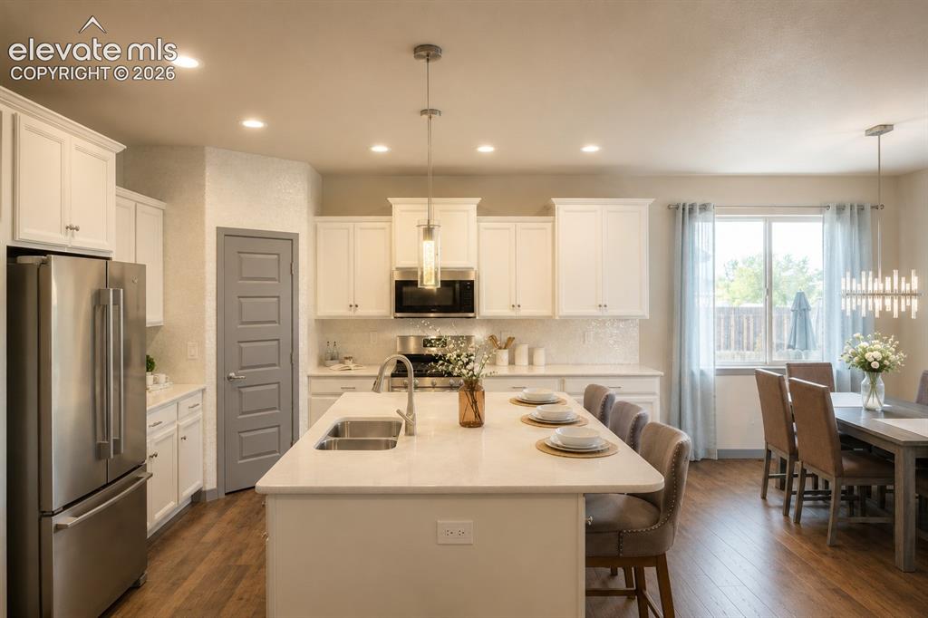 Image 4 of 31: Bright kitchen with opal backsplash, quartz surfaces, stainless appliances 