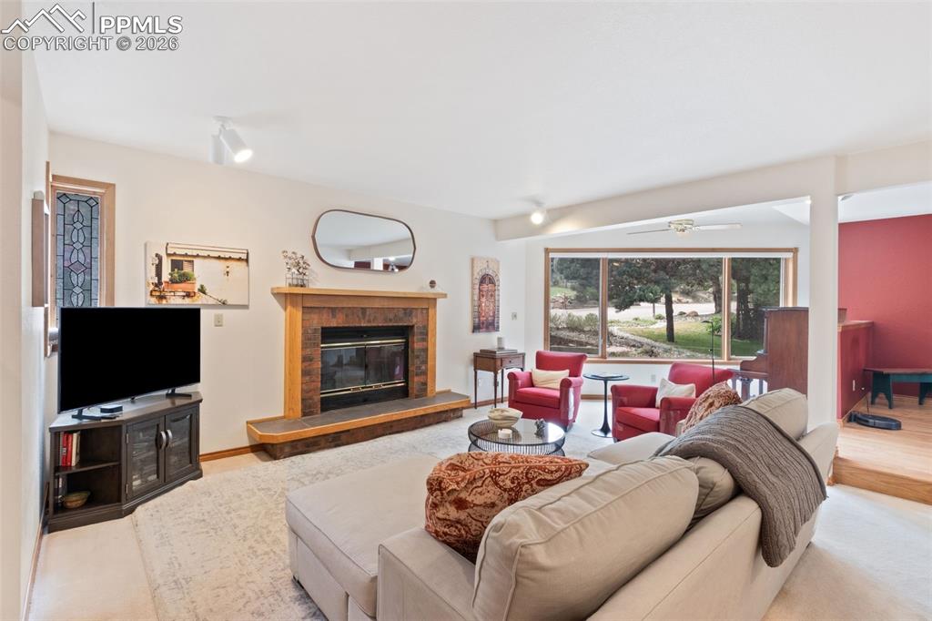 Image 13 of 47: Living room featuring wood burning fireplace and large windows for a lot of