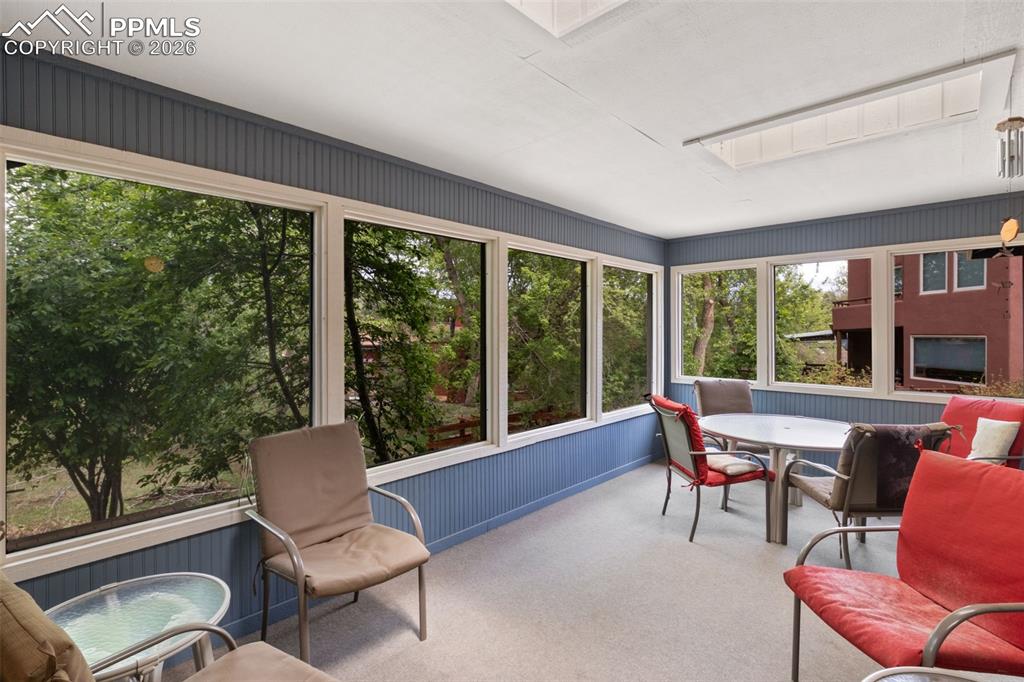 Image 24 of 47: Sunroom featuring expansive windows, blue beadboard wainscoting, white base