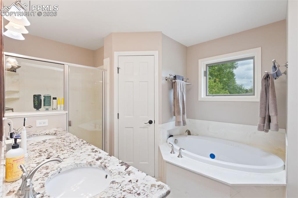 Image 29 of 47: Bathroom featuring a white corner soaking tub, a large window, a glass-encl
