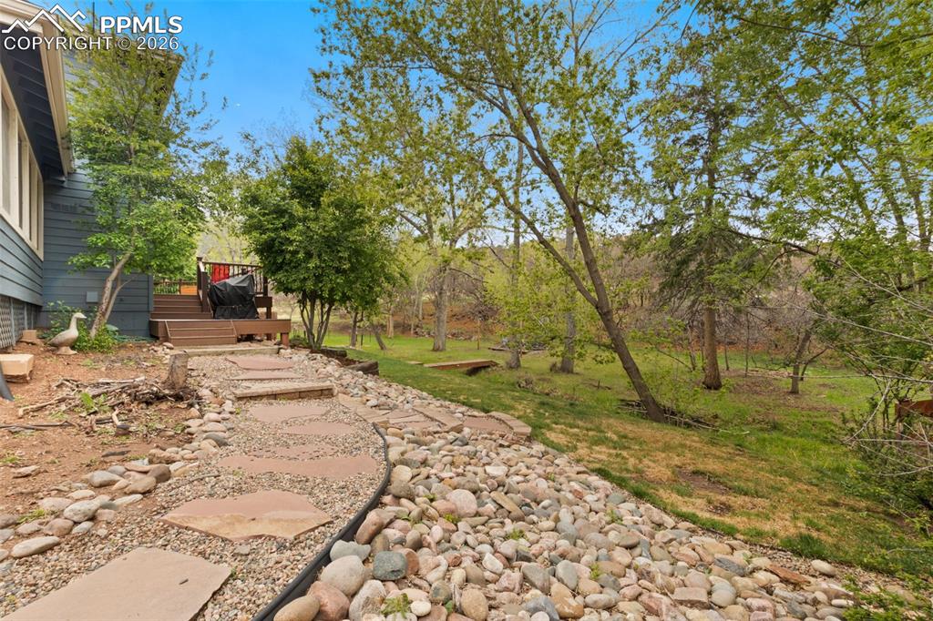 Image 44 of 47: Curved flagstone pathway with river rock edging leading to a multi-level wo