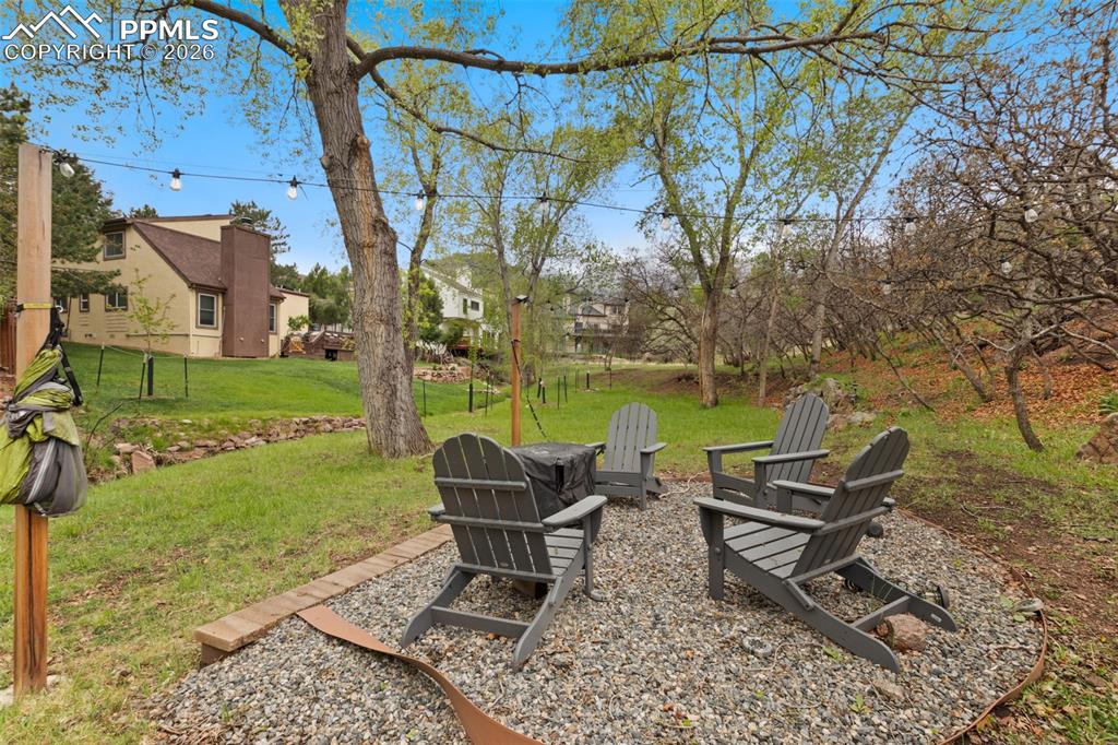 Image 46 of 47: Outdoor seating area next to creek featuring a gravel patio and string ligh