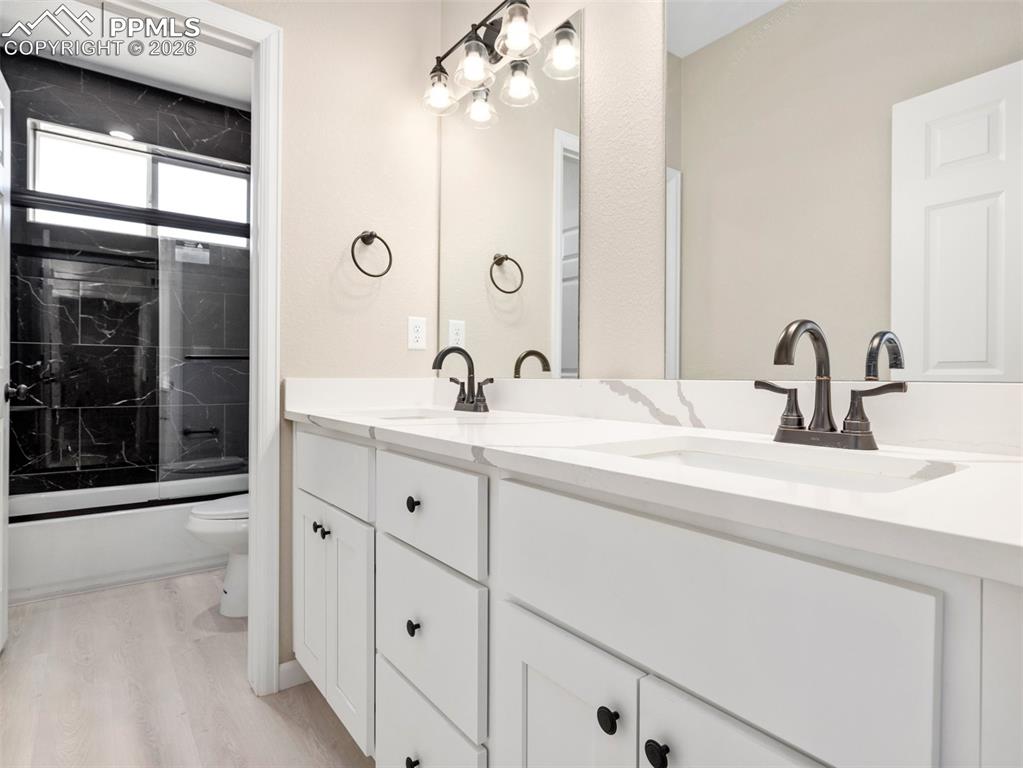 Image 19 of 26: Main Bath with double vanity, quartz countertops and custom tile in the tub
