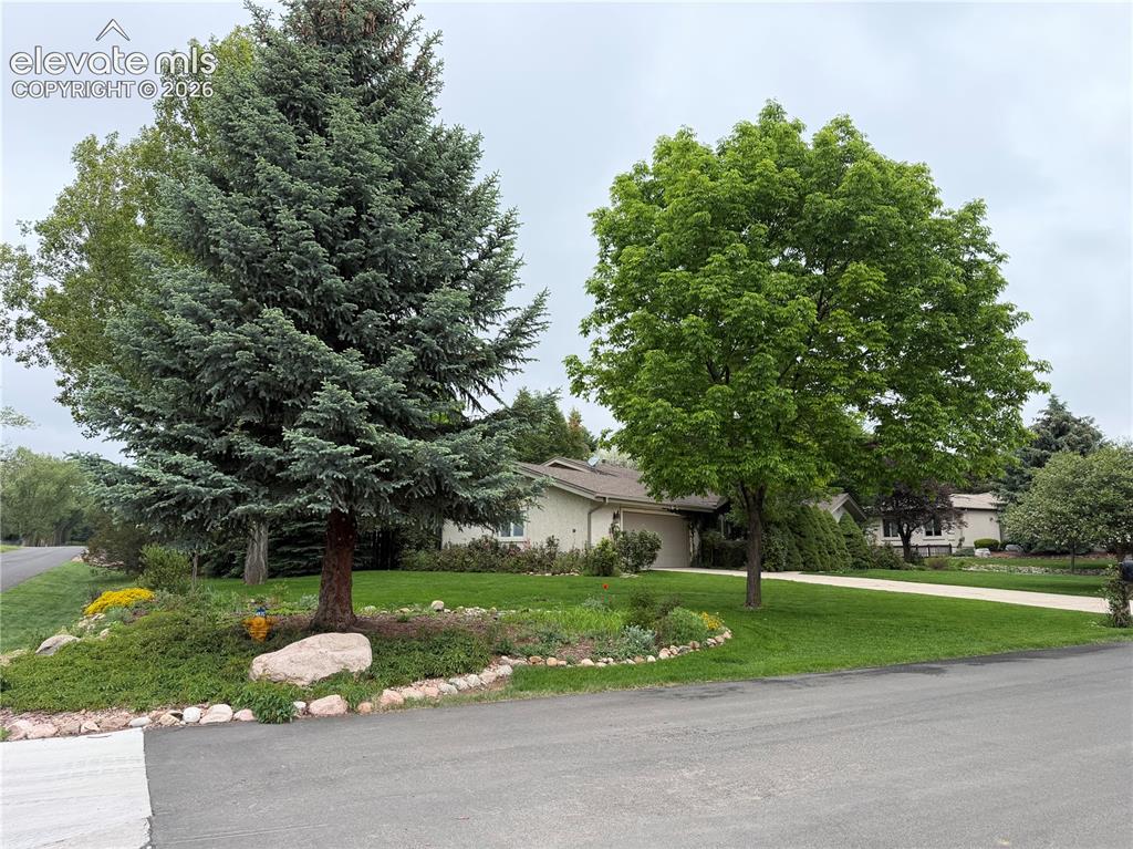 Image 7 of 21: Residential property featuring a sprawling green lawn, mature trees, and la