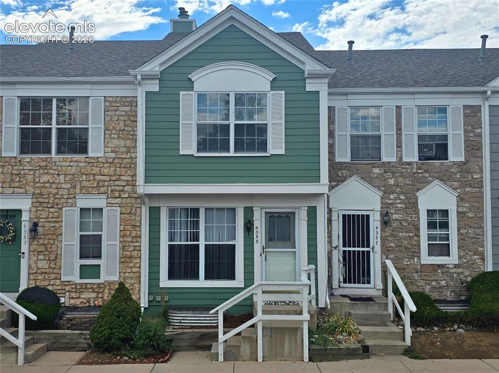 Caption: Exterior featuring stone veneer and horizontal siding, with white window shutters and multiple windo