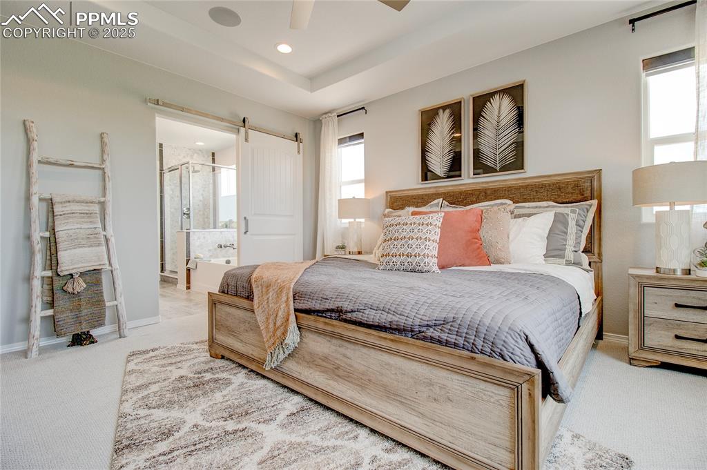 Image 14 of 25: Bedroom featuring carpet, a barn door, ceiling fan, ensuite bathroom, and r