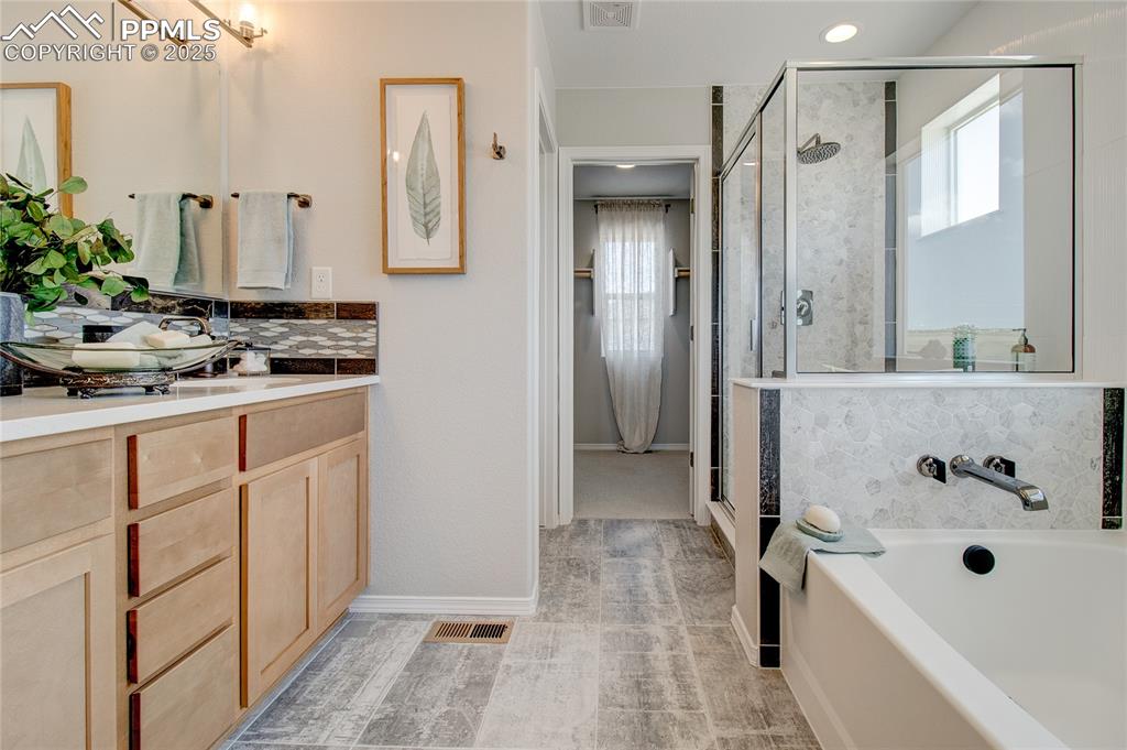 Image 16 of 25: Bathroom featuring backsplash, plenty of natural light, a garden tub, and v
