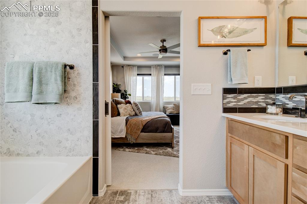 Image 17 of 25: Ensuite bathroom with vanity, a garden tub, a ceiling fan, and backsplash