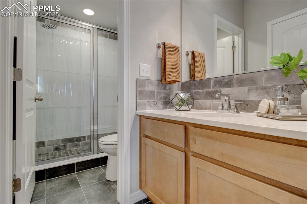 Image 25 of 25: Full bathroom with a shower stall, vanity, light tile patterned flooring, a