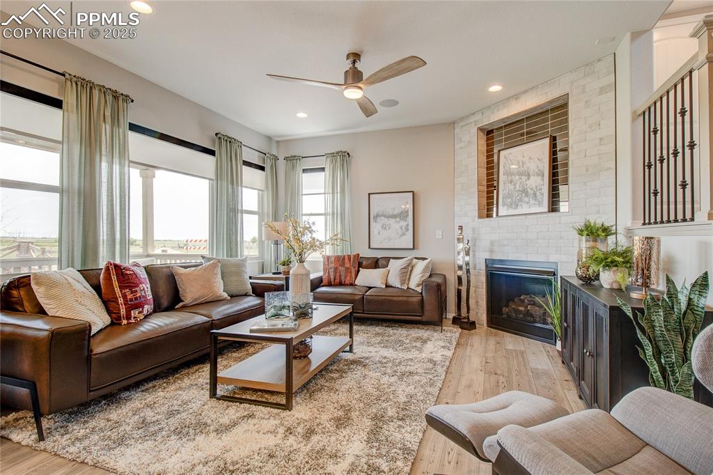 Image 3 of 25: Living area featuring light wood finished floors, ceiling fan, a brick fire