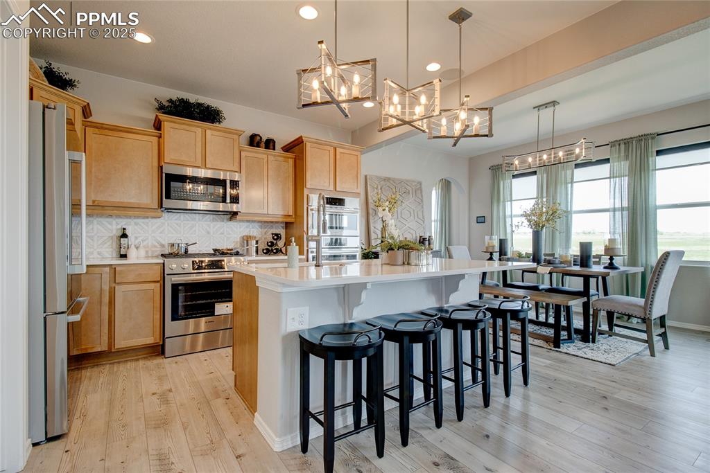 Image 4 of 25: Kitchen featuring arched walkways, decorative backsplash, a breakfast bar, 