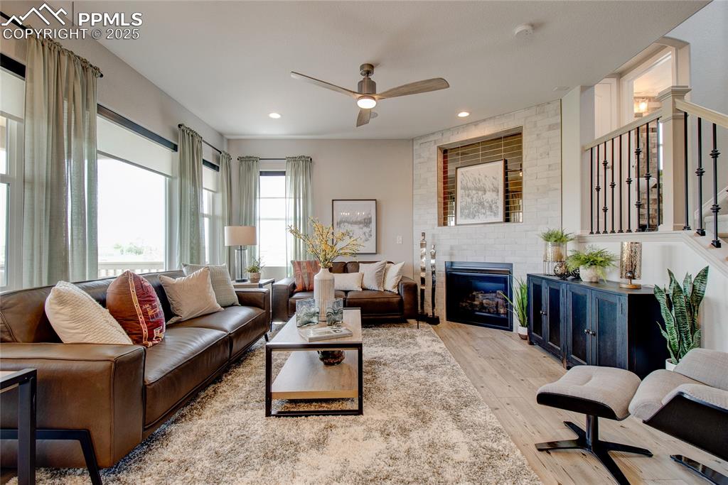 Image 5 of 25: Living area with a fireplace, light wood-type flooring, and ceiling fan