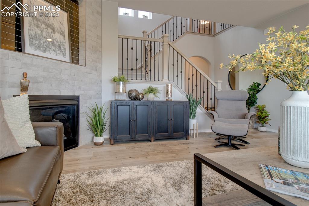 Image 6 of 25: Sitting room featuring light wood-style flooring and a glass covered firepl