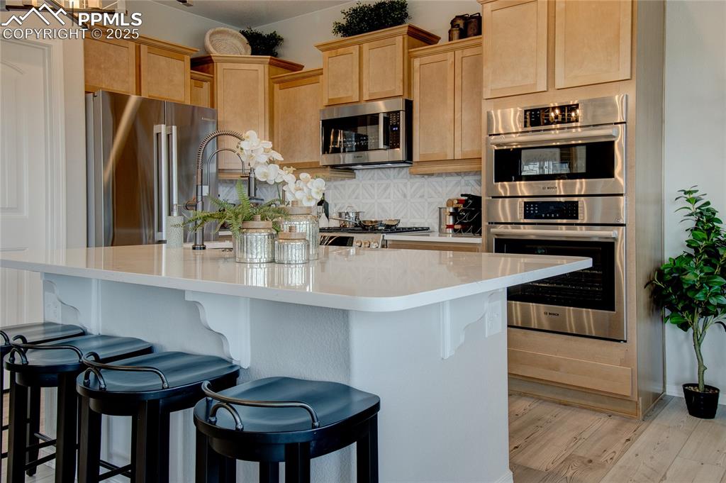 Image 7 of 25: Kitchen featuring light brown cabinets, appliances with stainless steel fin